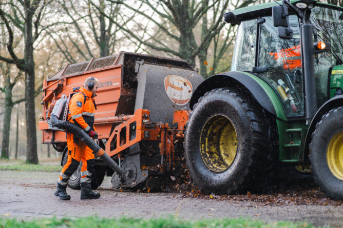 Medewerkers van de buitendienst met tractor en bladblazer