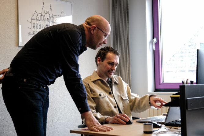 Medewerkers overleggen achter een computer
