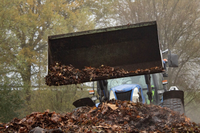 Tractor schept bladeren op een hoop